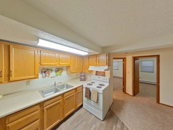 A kitchen with wooden cabinets and a white stove top oven.
