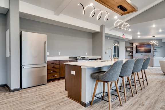 a kitchen with a island and chairs in front of a refrigerator. Circle Pines, MN Lexington Lofts