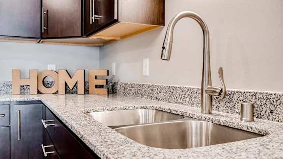 a kitchen with a sink and home letters on the counter. Circle Pines, MN Lexington Lofts