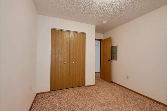 a bedroom with a closet and a door to a hallway. Fargo, ND Country Edge Apartments