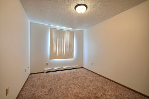 a  bedroom with a window and a window shade. Fargo, ND Country Edge Apartments