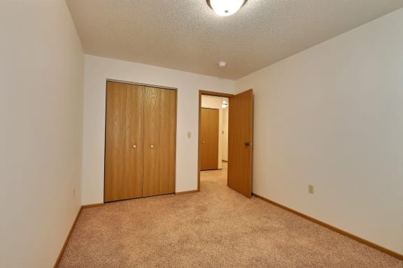 a  bedroom with carpet and a door to a bedroom. Fargo, ND Country Edge Apartments