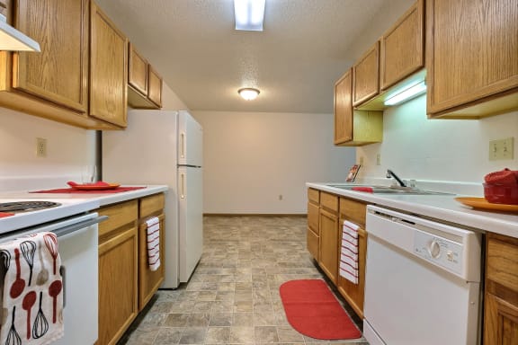 a kitchen with white appliances and wooden cabinets. Fargo, ND Country Edge Apartments