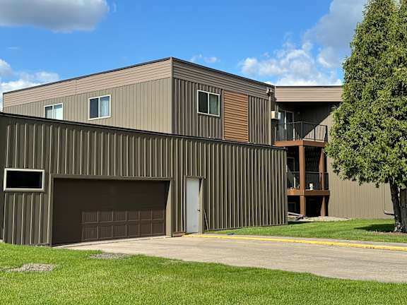 A modern house with a garage door and a tree in front. Grand Forks, ND Cedarwood Apartments