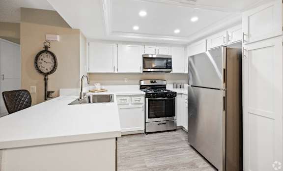 A modern kitchen with a white countertop and stainless steel appliances. at The Oaks Apartments, California, 91786