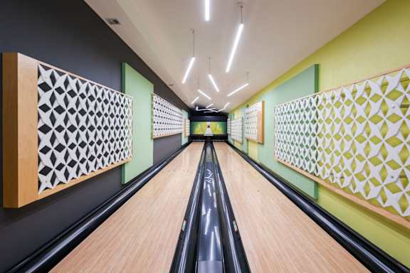 A bowling alley with wooden lanes and green walls.