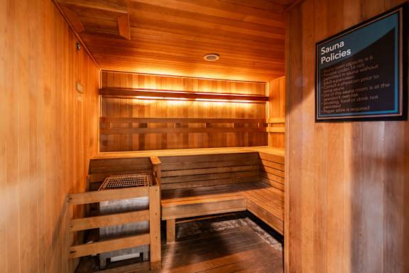 A sauna room with wooden benches and a sign that reads "Sauna Policies".