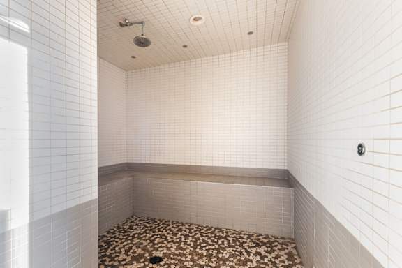 A shower area with a tiled floor and walls.