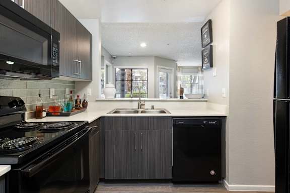 A modern kitchen with black appliances and a black fridge.