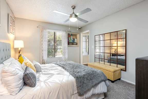 A bedroom with a bed, a bench, and a ceiling fan.