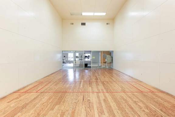 A large empty room with wooden flooring and white walls.