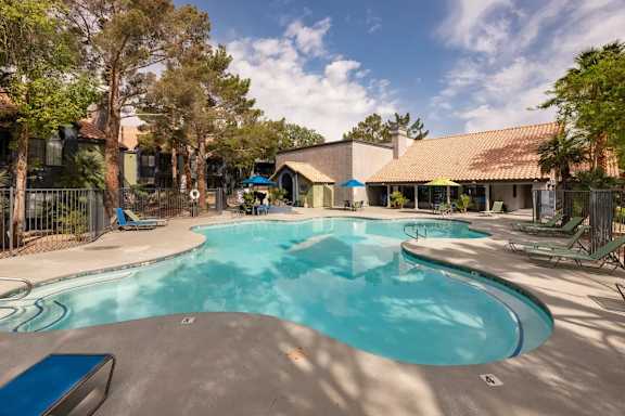 A large outdoor swimming pool surrounded by trees and lounge chairs.