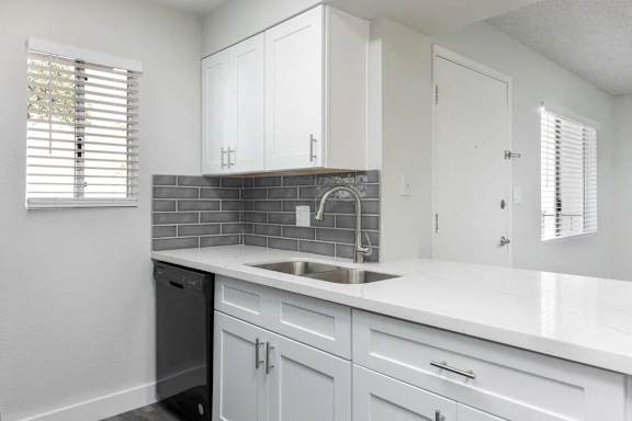 A kitchen with white cabinets and a black dishwasher.