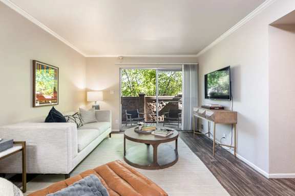 A living room with a white couch and a glass coffee table.