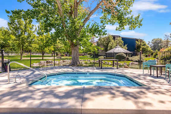 A pool surrounded by a fence with a tree in the middle.