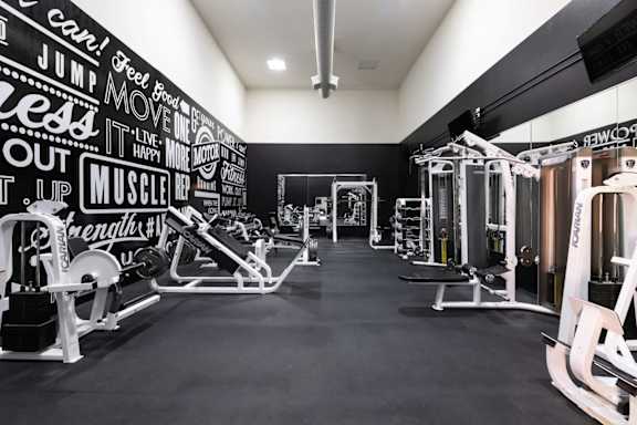 A gym with a black and white wall and various exercise machines.