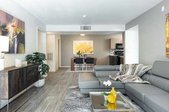 A modern living room with a grey sofa, a wooden cabinet, and a painting on the wall.