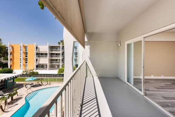 A balcony with a pool and a building in the background.