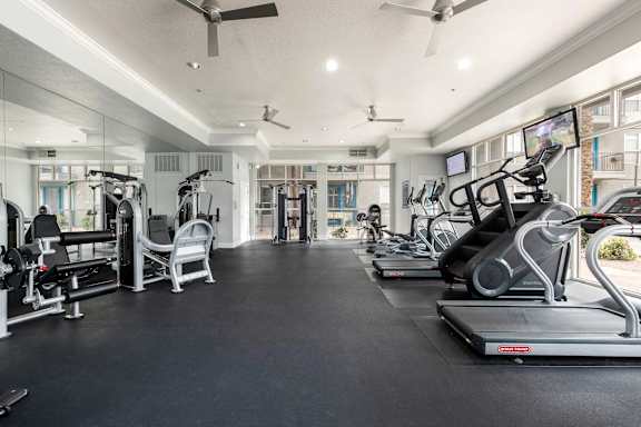A spacious gym with a variety of equipment including treadmills, stationary bikes, and weight machines.