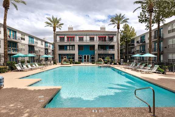 A large swimming pool surrounded by palm trees and lounge chairs.