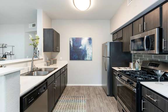 A modern kitchen with black cabinets and stainless steel appliances.