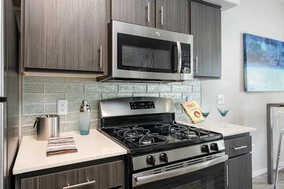 A modern kitchen with a stove, microwave, and oven.