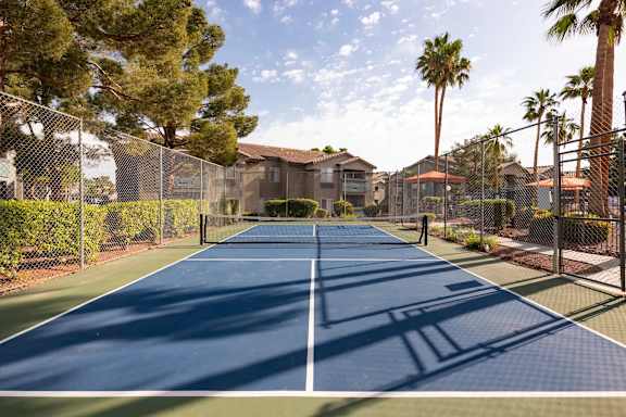 A tennis court surrounded by a fence and trees.