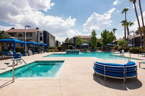A large outdoor swimming pool with a blue pool ladder and a blue poolside lounge chair.