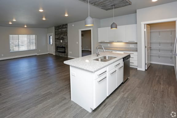 a kitchen with white cabinets and a white island with a stainless steel sink at Mezzo Apartments, North Dakota, 58104