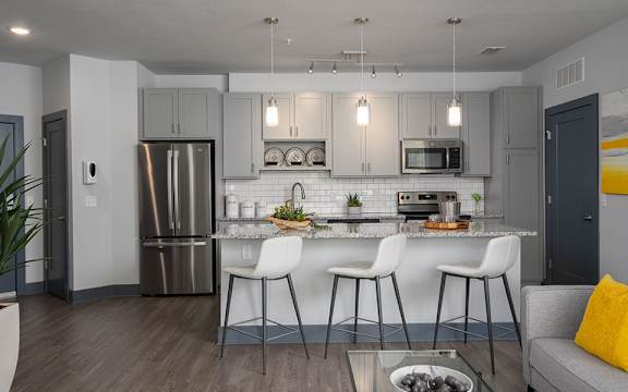 A modern kitchen with a bar stool and a dining table.