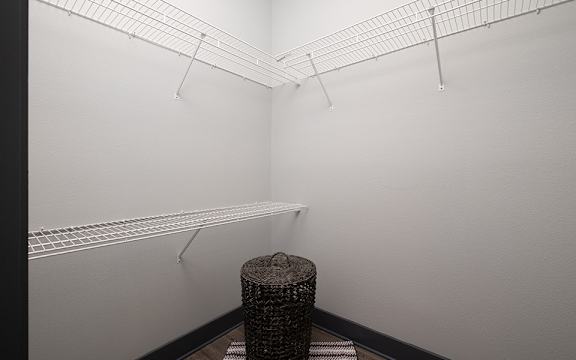 A room with a white wall and a black trash can.
