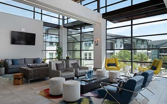 A modern living room with a large window and a flat screen TV mounted on the wall.