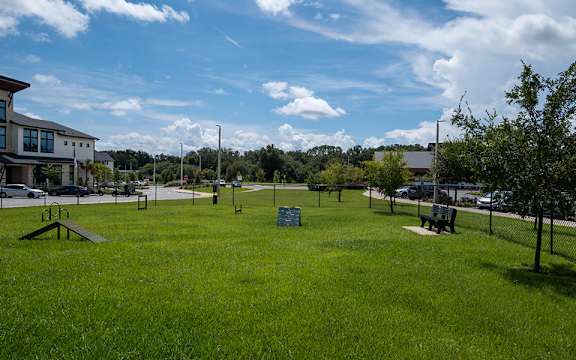 A park with a green sign in the middle of a grassy area.
