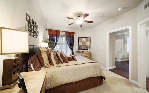 A bedroom with a bed, a ceiling fan, and a window with curtains.