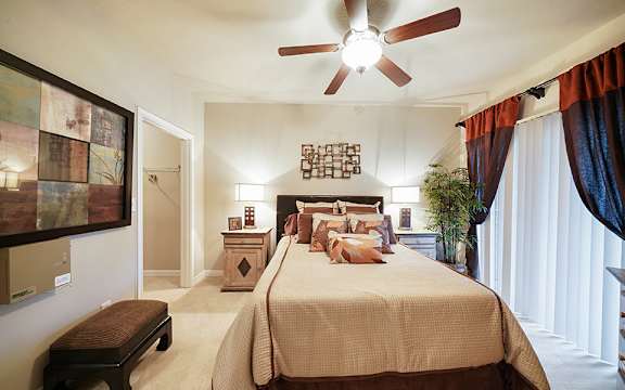 A bedroom with a large bed and a ceiling fan.