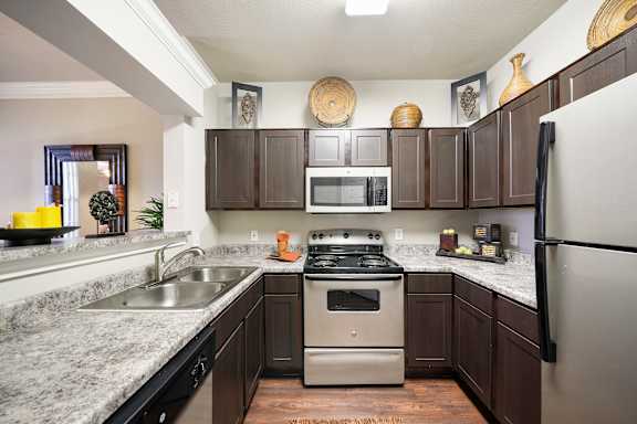 A kitchen with a stove, sink, and refrigerator.