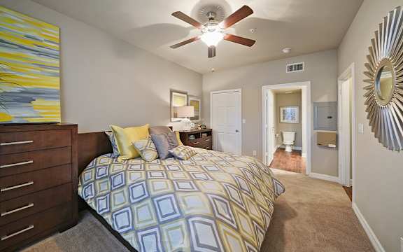 A bedroom with a bed, dresser, mirror, and a painting on the wall.