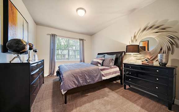 A bedroom with a bed, dresser, and mirror.