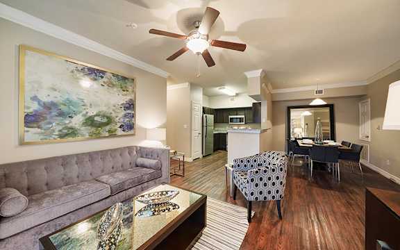 A living room with a grey couch and a painting on the wall.