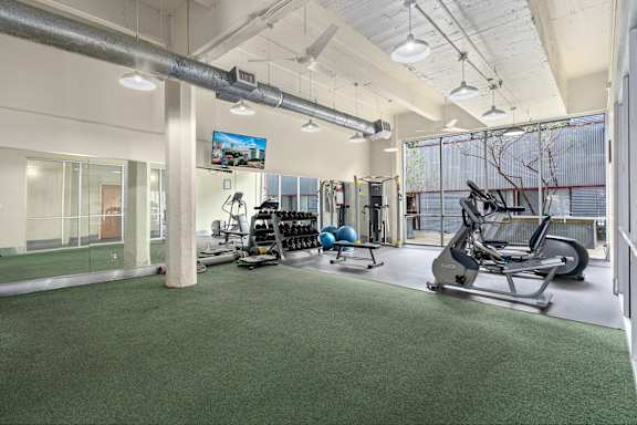 A gym with a variety of equipment including a treadmill, weights, and a stationary bike.