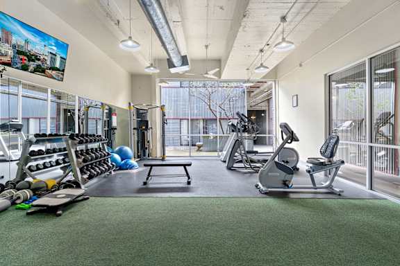 A gym with a variety of equipment including weights, a rowing machine, and a treadmill.