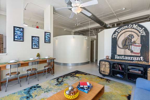 A room with a dining table and chairs, a sofa, and a wall mural of a restaurant.