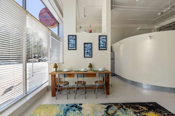 A dining room with a table set for two and a rug on the floor.