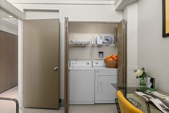 A small laundry room with a washer and dryer and a basket of clothes.