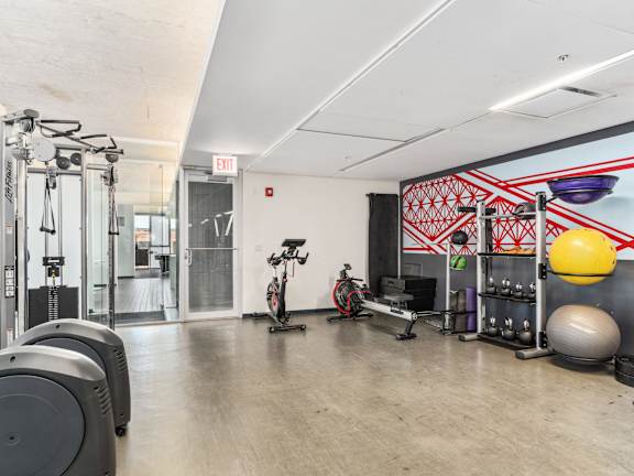A gym with a variety of equipment including treadmills, weights, and exercise balls.