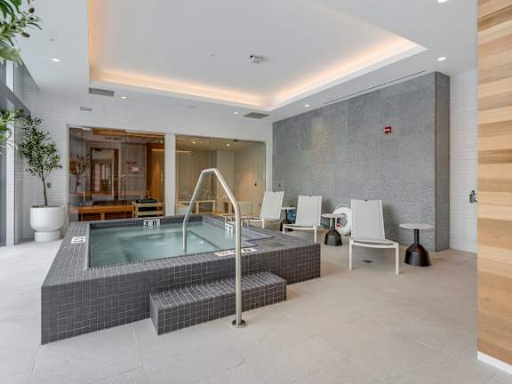 A modern indoor swimming pool with a glass enclosure and a metal ladder.