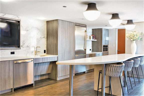 A modern kitchen with a white table and grey chairs.