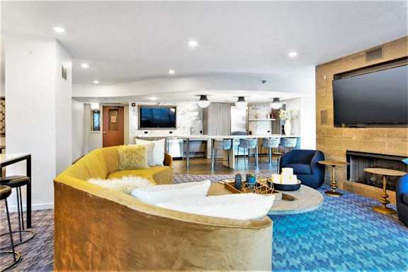 A modern living room with a curved gold couch and a television on the wall.