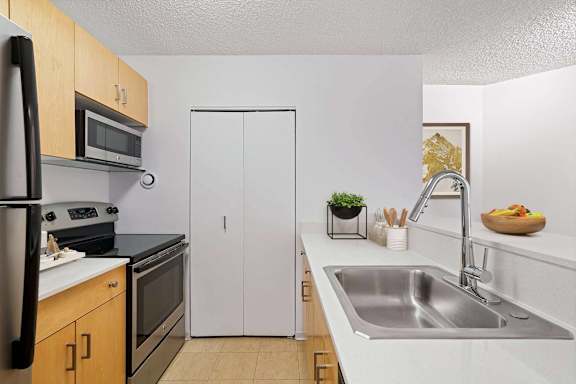 A kitchen with a white sink and a white refrigerator.
