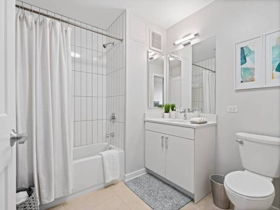 A white bathroom with a shower, sink, and toilet.